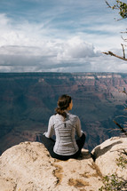 woman sitting at the edge of a canyon landscape 