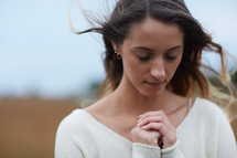 face of a young woman praying outdoors 