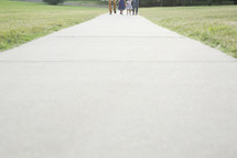 distant family walking outdoors holding hands 