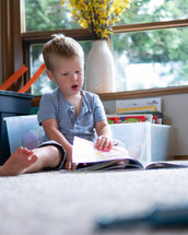 toddler boy reading a book 