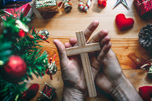 hands holding a cross, praying at Christmas 