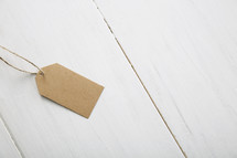 A brown paper gift tag on a white table.