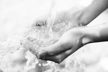 Hands under fresh well water at a spigot 