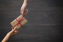 One person giving a wrapped gift to another.