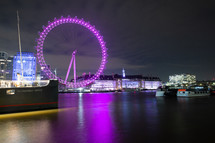 purple ferris wheel by a waterway at night 