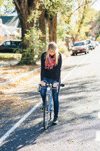 a woman riding a bike down a neighborhood street 