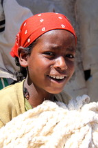 A young Ethiopian girl holding cotton cords at a local cotton mill  [For similar search for Ethnic Smile Face]