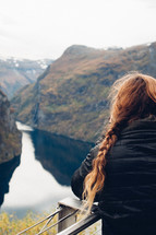 a woman with braided hair looking out at a lake in a canyon
