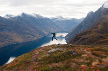 a man leaping in the air and a lake in a valley 