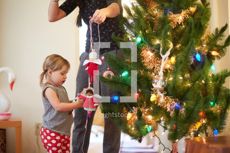mother and daughter decorating a Christmas tree