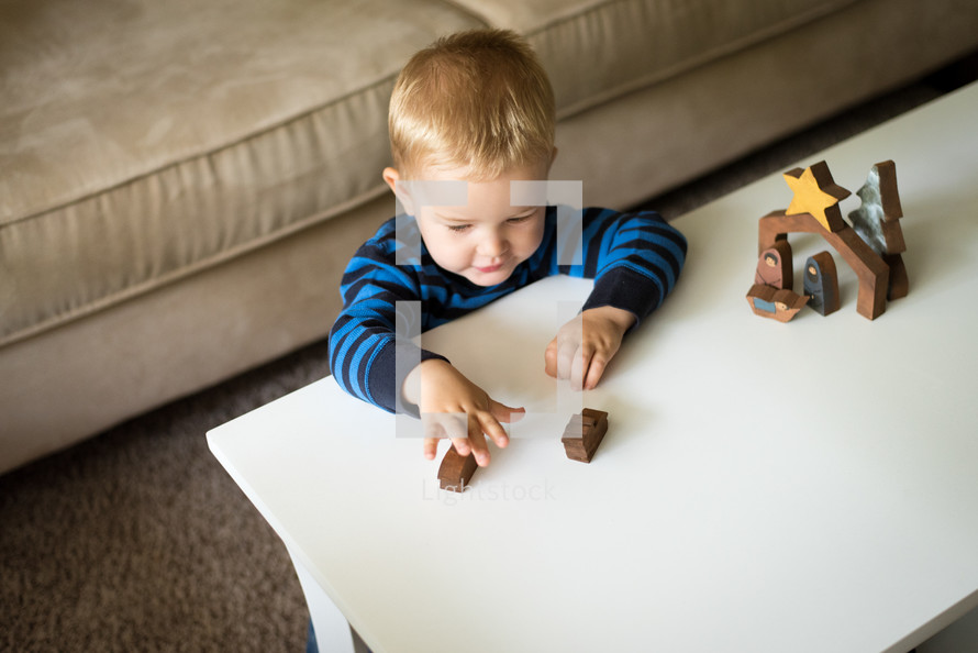 a toddler playing with a wooden nativity 