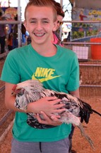 a child holding a chicken at a petting zoo 