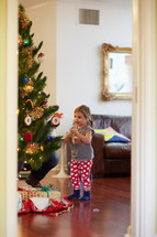 a little girl decorating a Christmas tree