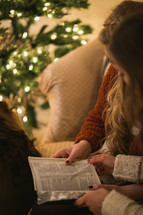 Two women reading the Bible together near a Christmas tree.