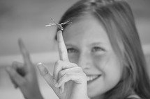 a little girl catching a dragonfly on her finger 