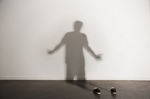 shadow of a man shrugging and shoes on the floor 