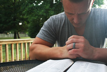 a man praying over a Bible outdoors 