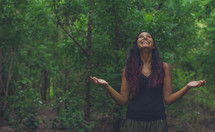a woman looking up to God standing in a forest 