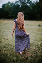 teen girl walking in a field wearing a long dress
