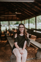 teen girl sitting in pews of an outdoors church 