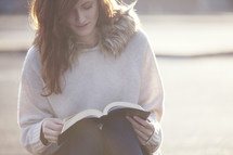 Woman sitting and reading the Bible outside.