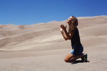 a woman kneeling in sand 