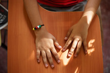 overhead view of a child's hands on a desk 