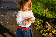 toddler girl playing with fall leaves 