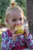 toddler girl eating an apple 