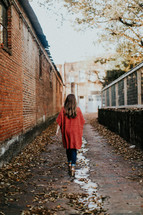 a woman walking down an alley in fall 