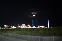 The moon over a seaside amusement park at night 