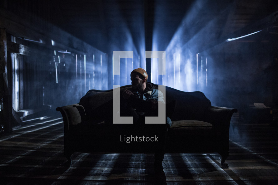 man sitting on a couch in a dark room 