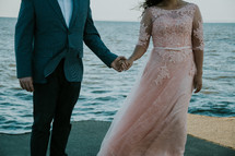 bride and groom on a beach holding hands 