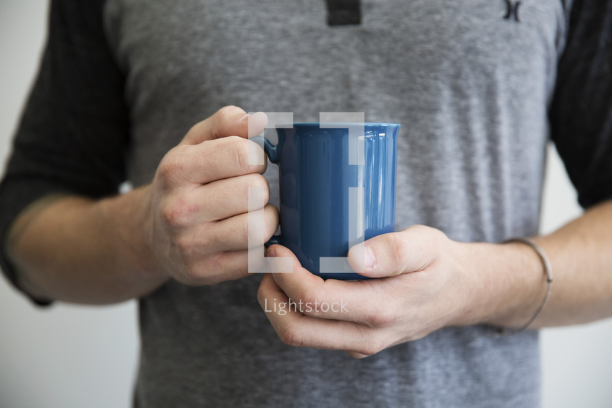 A man holding a blue coffee mug.