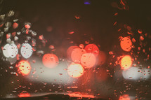 Red and white bokeh lights through raindrops