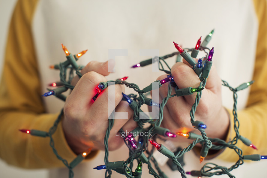 a man holding tangled Christmas lights.
