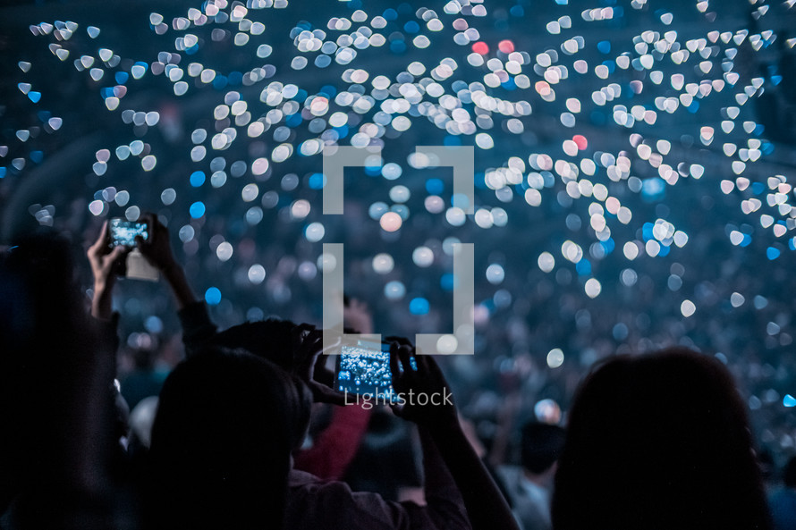 crowds holding up cellphone lights at a concert 