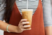 a woman holding an iced coffee 