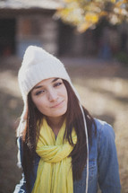 A young woman smiling and wearing a white beanie