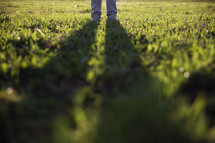 man standing in grass with shadow