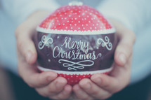 a large red ornament with the words Merry Christmas being held in someone's hands