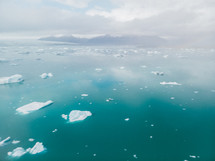 aerial view over icebergs floating in the ocean 