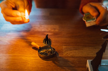 man lighting an incense burner on a wood table