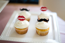 Cupcakes topped with lips and mustaches.