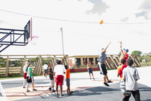 Teens playing basketball outside.