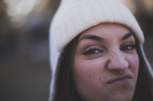 A young woman making a funny face and wearing a white beanie