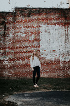 portrait of a young woman standing in front of a brick wall 