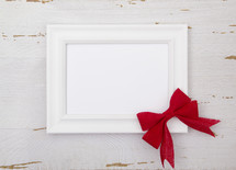 frame with white paper and red bow 