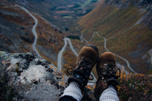 feet in boots hanging off a mountainside 
