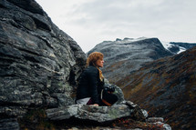 a woman sitting on a rocky mountainside 